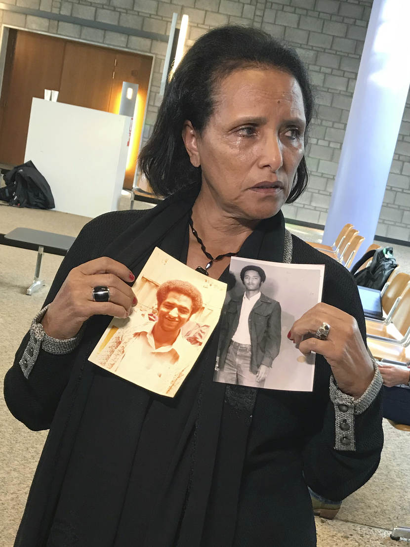 Een nabestaande is aanwezig bij de rechtszaak in Den Haag en houdt foto’s van haar in 1978 omgekomen broer vast.